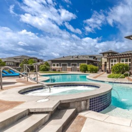a courtyard with a pool and buildings in the background