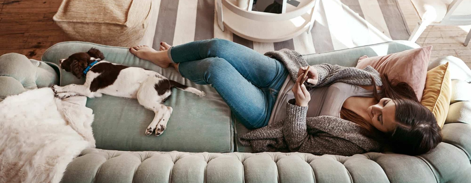 a woman and a dog laying on a couch with a phone